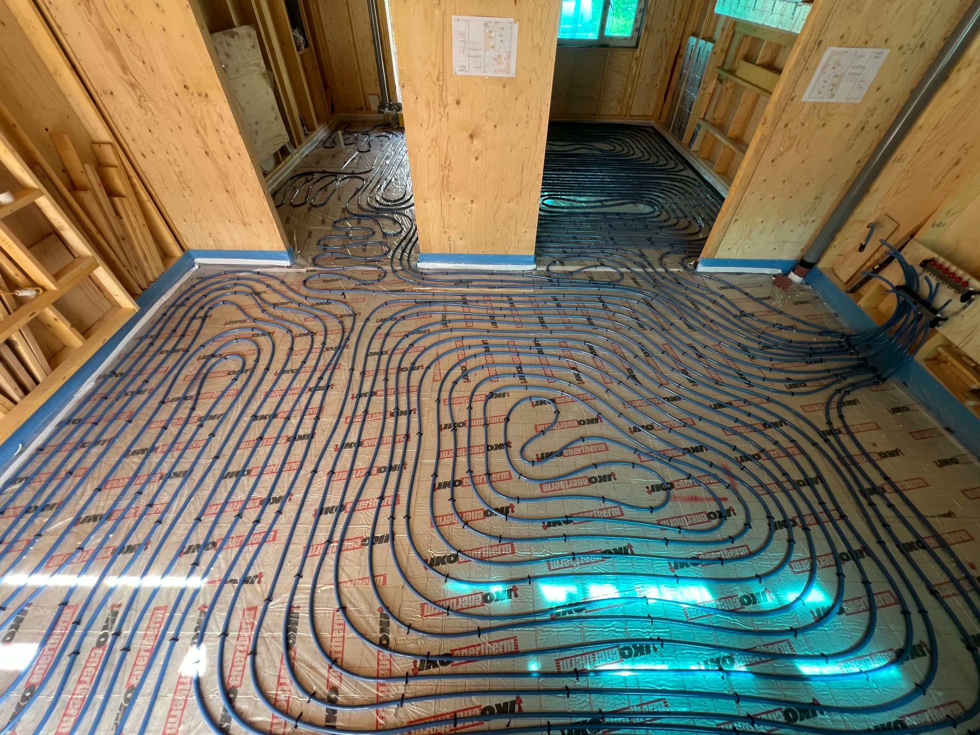 Underfloor heating pipe loops laid out on insulation boards in a timber-frame new build near St Austell, Cornwall